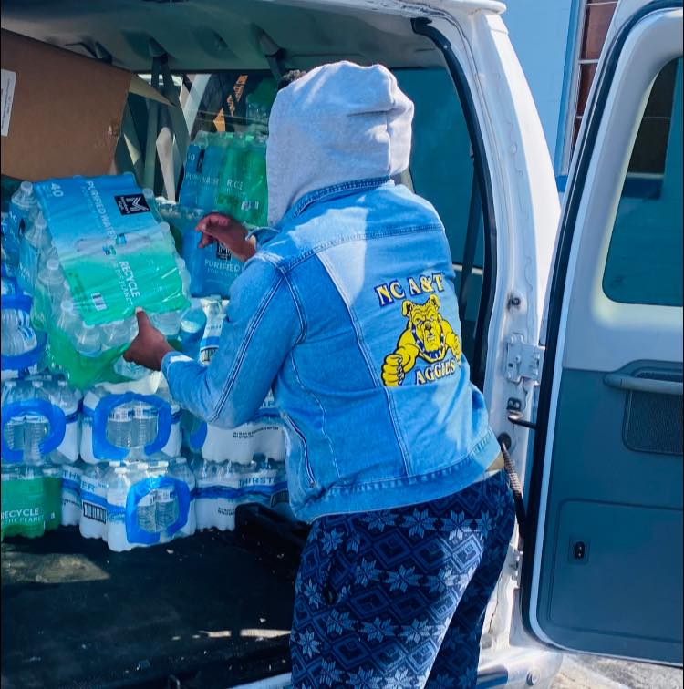 Someone getting a case of water out of a van.